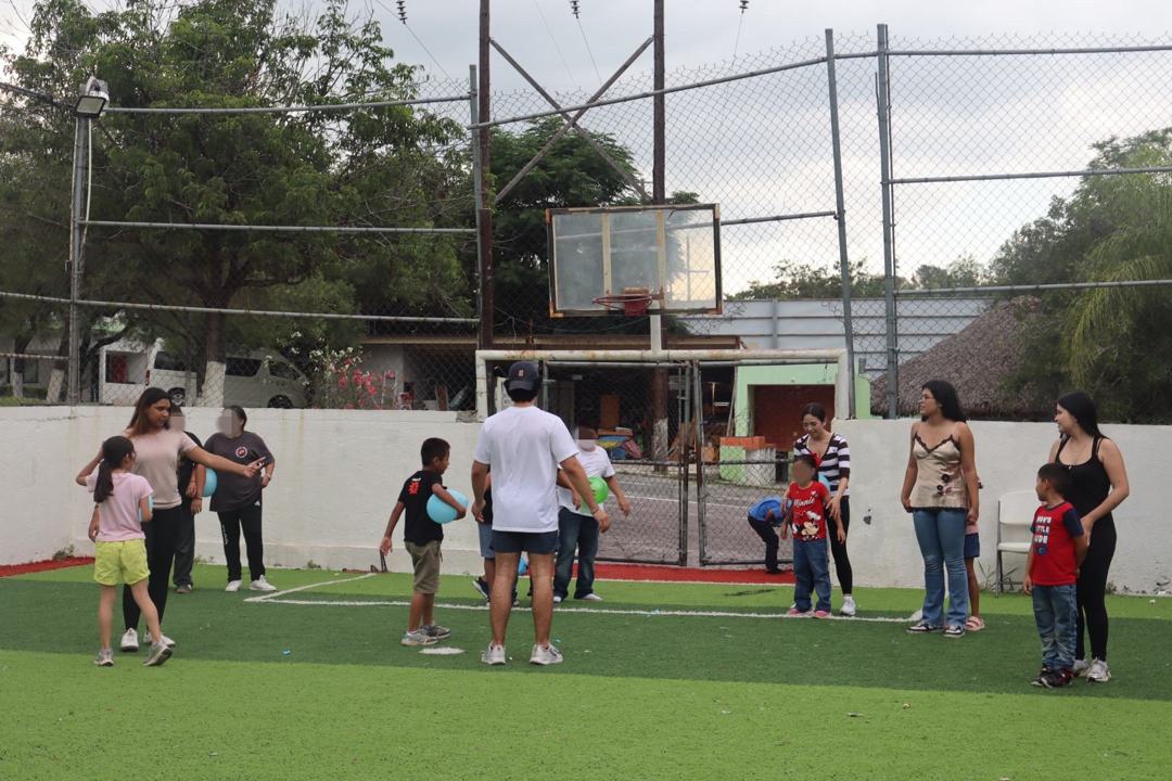 Niños y voluntarias jugando con globos en la cancha